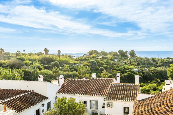 Un pueblo costero con tejados de tejas rojas, abundante vegetación y una vista despejada del mar.