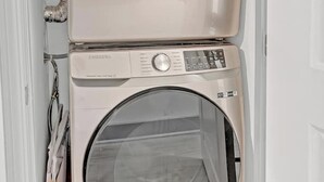 A stacked washer and dryer unit in a laundry room. - Tropical Delight Studio Suite (Atlanta)