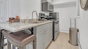 A modern kitchen with a granite countertop, stainless steel appliances, and a built-in oven. - Tropical Delight Studio Suite (Atlanta)