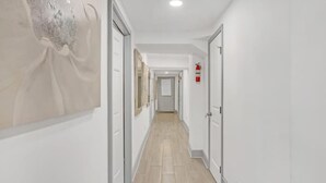 A hallway with white walls, light wooden flooring, and doors leading to rooms. - Bahama Mama Studio Suite (Atlanta)