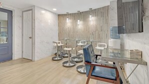 A modern dining area with a glass table, multiple bar stools, and a wooden floor. - Bahama Mama Studio Suite (Atlanta)