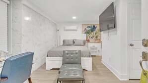 Une chambre à coucher avec un lit, un bureau, une chaise et un téléviseur.
