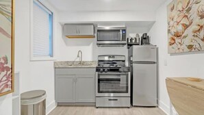 Une cuisine compacte équipée d’un four, d’un micro-ondes et d’un réfrigérateur intégrés.