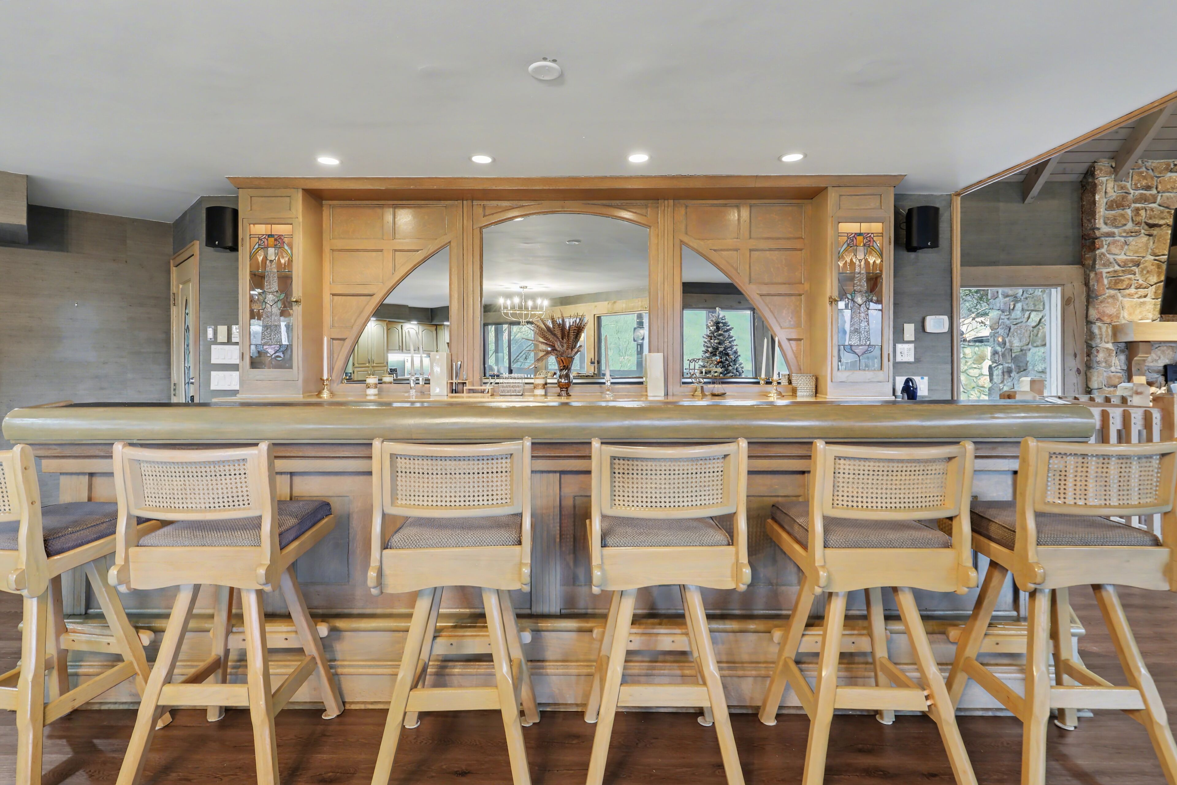 Une cuisine dotée d’un îlot central, de tabourets de bar en bois et d’un mur d’accent en pierre.