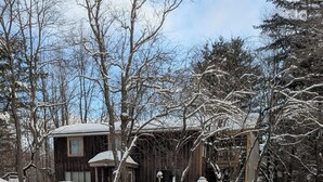 Een besneeuwd landschap met een houten chalet en een picknicktafel.