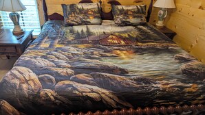Een bed met een ontwerp geïnspireerd door een bos en een blokhut, een houten hoofdbord en twee bedlampjes.