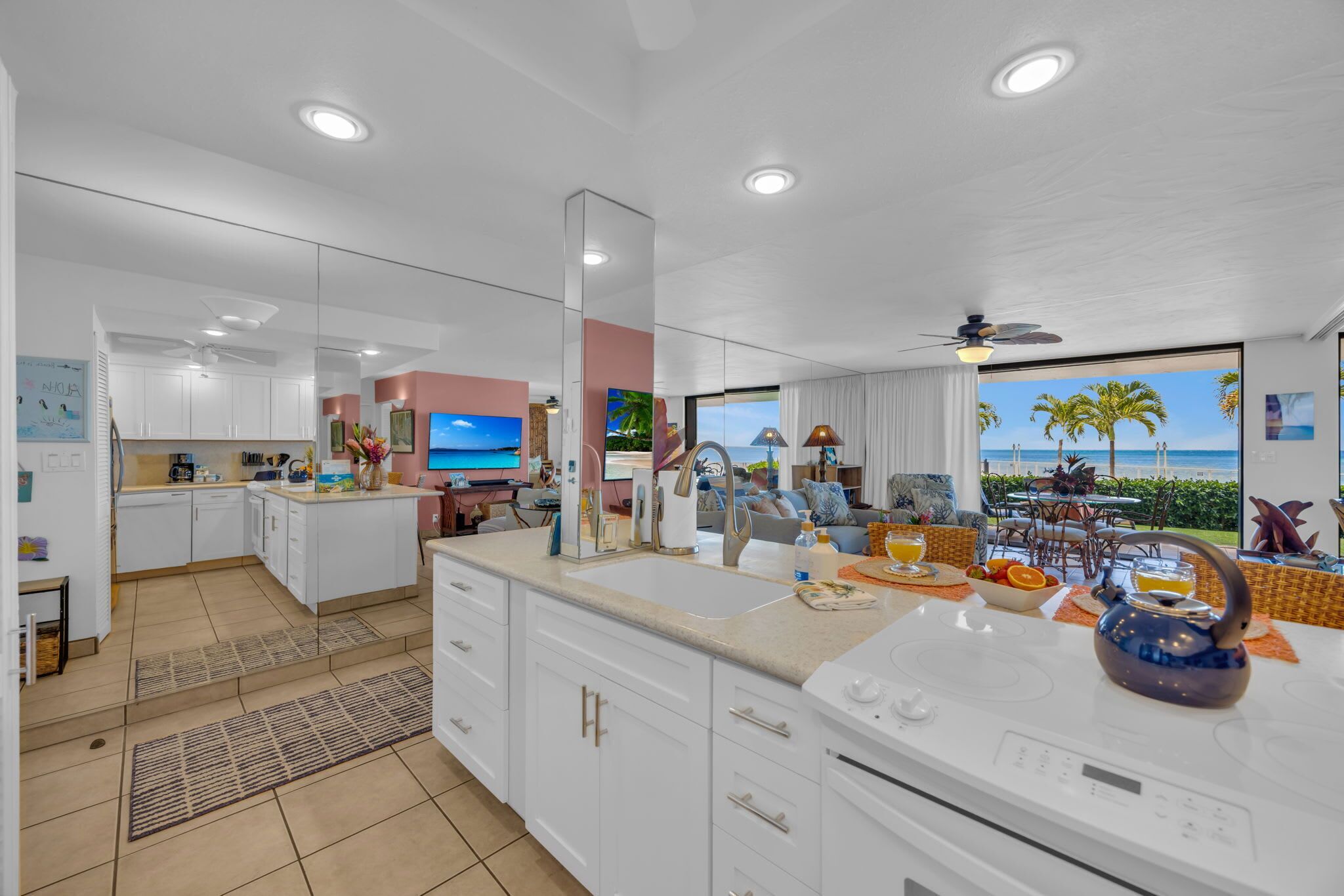 A modern kitchen with a large island, a dining area with a view, and a living space with a TV.