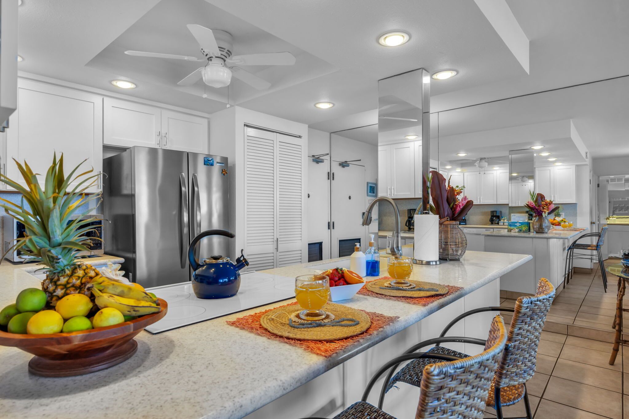A modern kitchen with a central island, stainless steel appliances, and a ceiling fan.