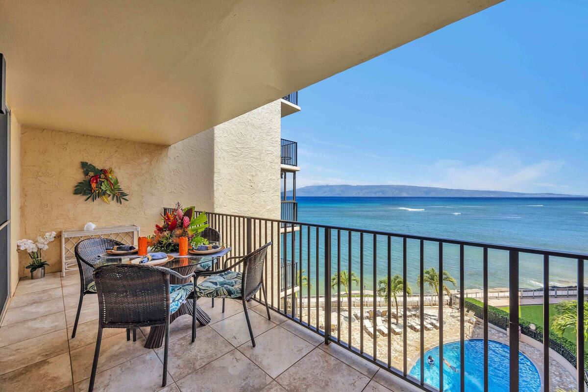 A balcony with a table, chairs, and a view of the ocean.