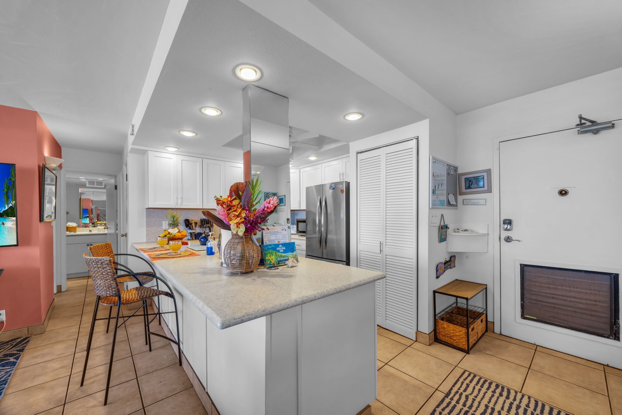 A modern kitchen with white cabinets, a central island, and a refrigerator.