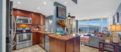 A modern kitchen with stainless steel appliances, a wooden island, and a large window overlooking a scenic view.
