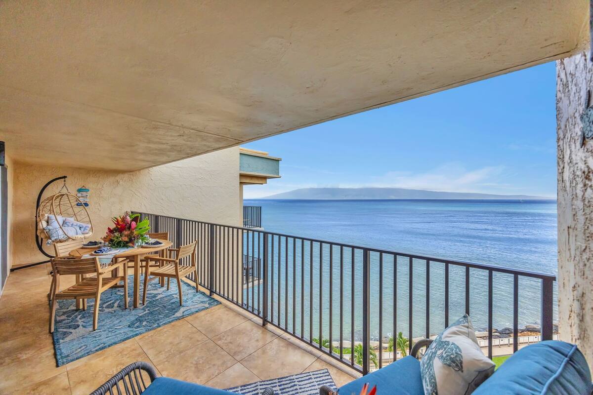 A balcony with a table and chairs, a view of the sea, and a railing.