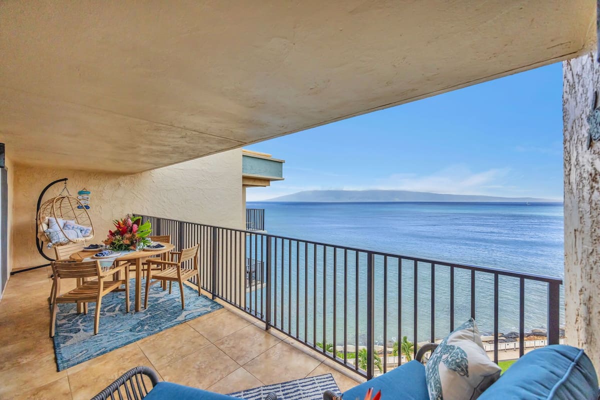 A balcony with a table and chairs, a view of the sea, and a railing.