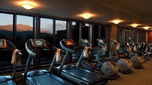 Gimnasio con cintas de correr y máquinas elípticas, ventanas amplias con vista a la montaña y equipamiento de ejercicio con pantallas digitales.