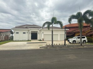 Une maison moderne à deux étages, dotée d’un garage, d’une allée et d’un VUS blanc garé devant.