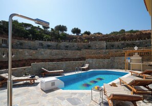 Une piscine avec des chaises longues et un mur en pierre.