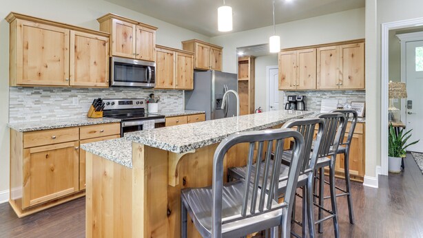 A modern kitchen with wooden cabinets, granite countertops, stainless steel appliances, and bar stools. - Modern Family Cabin: Walk to Table Rock Lake (Eureka Springs)