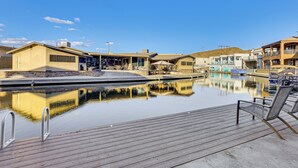 A tranquil pool area with a wooden deck, lounge chairs, and a clear blue sky. - Multi-Home Retreat on Colorado River w/ Boat Dock! (Parker)