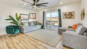 A living room with a grey sofa, a teal armchair, a large plant, and a ceiling fan. - Multi-Home Retreat on Colorado River w/ Boat Dock! (Parker)