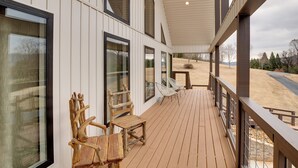 A wooden deck with outdoor seating and large windows. - Lakefront Guntersville Apt w/ Shared Dock! (Guntersville)