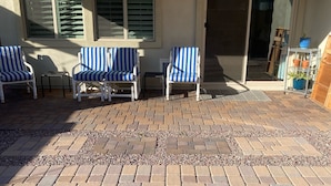 Un patio con suelo de ladrillo y dos sillas a rayas.