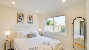 A bedroom with a bed, two bedside tables with lamps, a window with a view, and a wall-mounted mirror. - Business/Family Retreat Near Levi's Stadium! (Santa Clara)