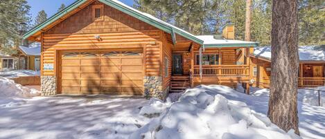 A log cabin with a stone foundation, a garage, and a porch.