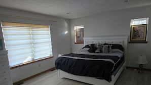 A bedroom with a bed, a dresser, a window with blinds, a lamp, and two framed pictures on the wall. - Charming 3-bedroom house MUST BE A LAND OWNER IN EAGLE ROCK RESORT (Hazleton)