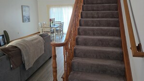 A staircase with wooden railings leading to a dining area with a table and chairs. - Charming 3-bedroom house MUST BE A LAND OWNER IN EAGLE ROCK RESORT (Hazleton)