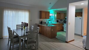 A spacious kitchen with wooden cabinets, a dining area with a table and chairs, and a view of the living area. - Charming 3-bedroom house MUST BE A LAND OWNER IN EAGLE ROCK RESORT (Hazleton)
