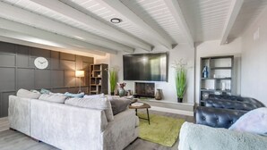 Una sala de estar moderna con un sofá gris, un sillón de cuero negro y un televisor de pantalla plana montado en la pared.