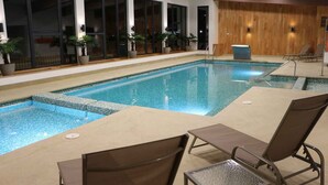 An indoor swimming pool with tiled edges, lounge chairs, and potted plants. - Apartment By Toore Patagonia (Natales)