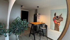 A modern living space with a dining area, a mirror reflecting a llama sculpture, and a cozy seating area with a plant. - Apartment By Toore Patagonia (Natales)
