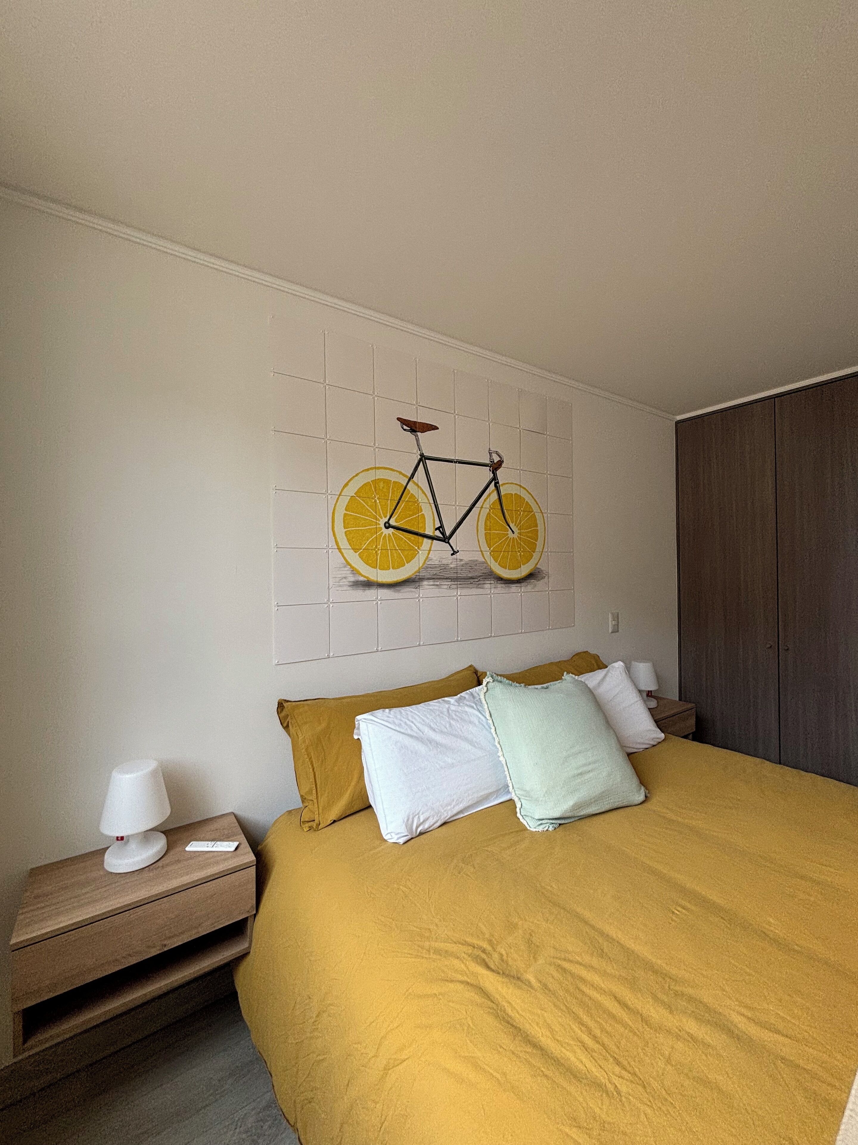A bedroom with a bed, a nightstand, a lamp, and a wall-mounted bicycle decoration.