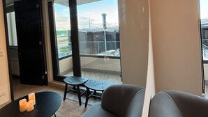 A modern living room with a sofa, a small table, and a view of the outside through large windows. - Apartment By Toore Patagonia (Natales)
