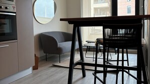 A modern kitchen with built-in appliances, a round mirror, and a dining area with a table and chairs. - Apartment By Toore Patagonia (Natales)
