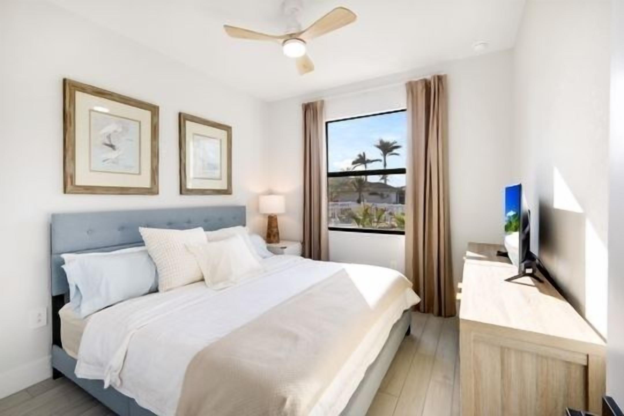 A hotel room with a bed, a desk, a TV, and a window with curtains.