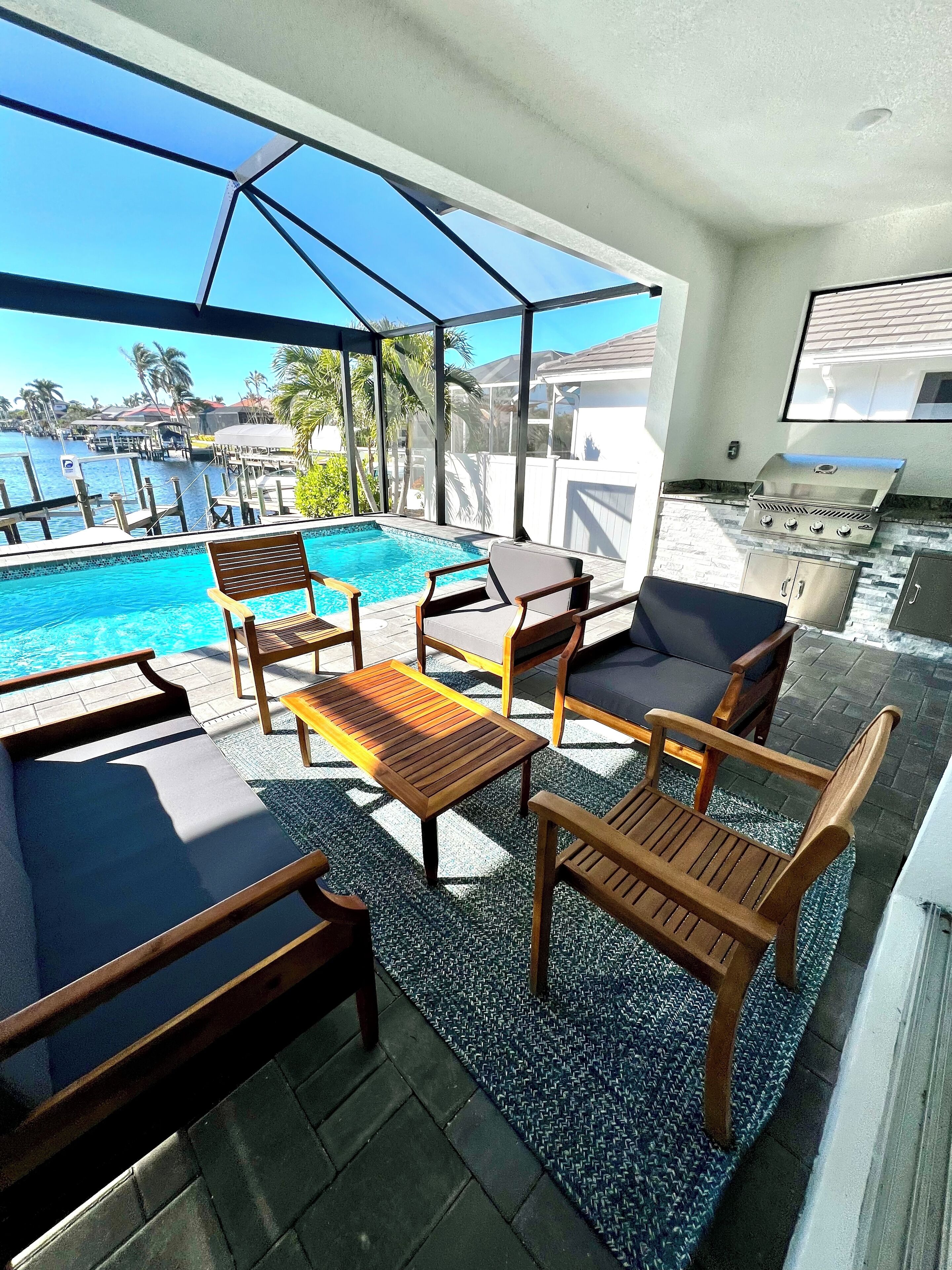 Un espace aménagé au bord de la piscine, avec des meubles en bois et une vue sur un port de plaisance.