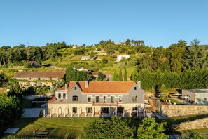 A large, two-story house with a red-tiled roof, surrounded by lush greenery and a small courtyard. - Tojeira Farmhouse (Mondrões)