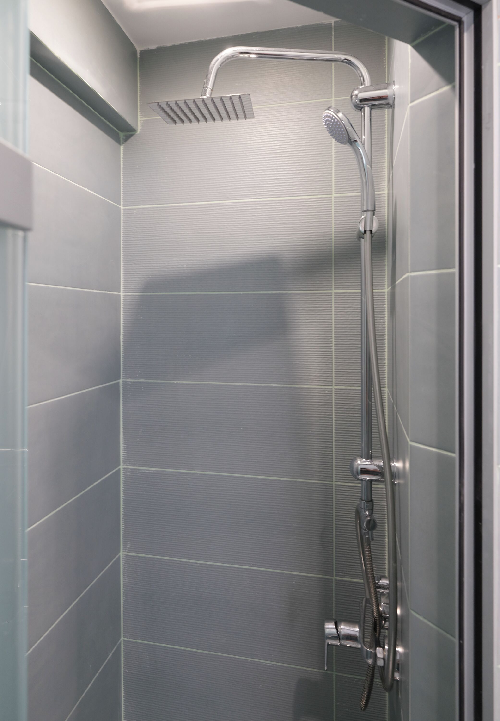 Une douche équipée d’un pommeau de douche à main et d’un pommeau de douche fixe fixé au mur.