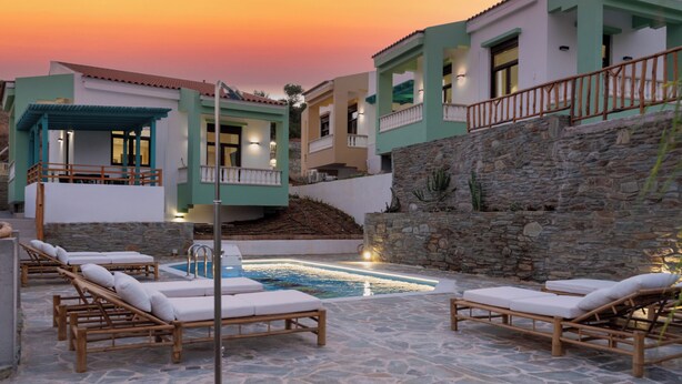 A poolside area with lounge chairs and a swimming pool, surrounded by buildings with stone walls and balconies. - Villa Akalis in Agia Pelagia close to beaches up to 7-8 quests (Agia Pelagia)