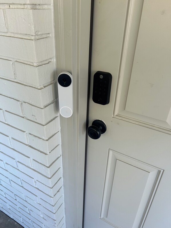 A white door with a Yale smart lock and a peephole.