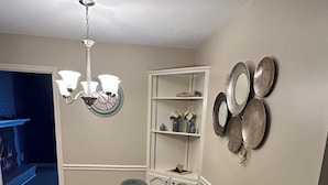 A dining area with a round wooden table, four green chairs, a chandelier, and decorative plates on the wall. - Soldier/Family Charming 3bed/2bath (Columbus)