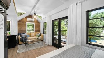 Une chambre moderne avec un grand lit, un plafond en bois et une vue sur l’extérieur.