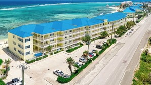 Un hotel de varios pisos con techo azul, situado cerca de una playa con aguas turquesas cristalinas.