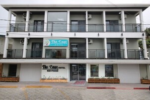 Een hotel met twee verdiepingen, met balkons en een bord met de tekst 'The Caye Hotel San Pedro'.
