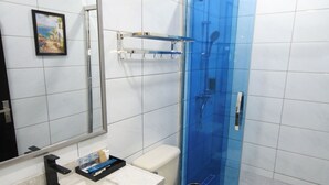 A modern bathroom with a white vanity, a large mirror, a toilet, and a glass-enclosed shower area. - The Caye Hotel San Pedro (San Pedro)