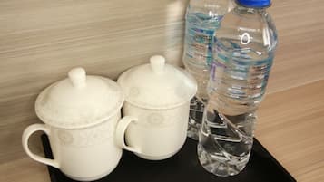 Un plateau avec deux tasses en céramique blanche et deux bouteilles d’eau avec des bouchons bleus, portant l’inscription « THE CAYE HOTEL ».