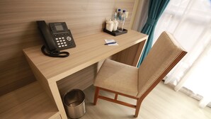 A hotel room with a wooden desk, a telephone, a chair, a trash bin, and a small table with bottles and a cup. - The Caye Hotel San Pedro (San Pedro)