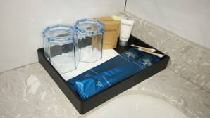 A bathroom tray with toiletries including a shower cap, conditioner, and a toothbrush. - The Caye Hotel San Pedro (San Pedro)